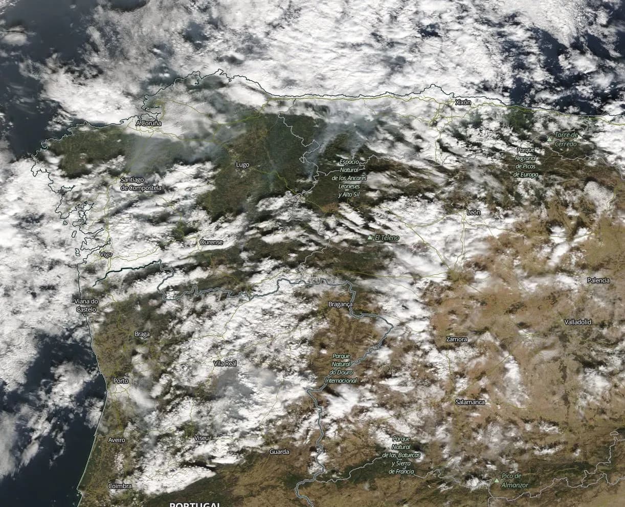 Satellite view of north-western Iberia under patchy white cloud, with brown and green land, place names such as Porto, Viseu and Coimbra, and thin grey smoke plumes drifting north over Galicia.