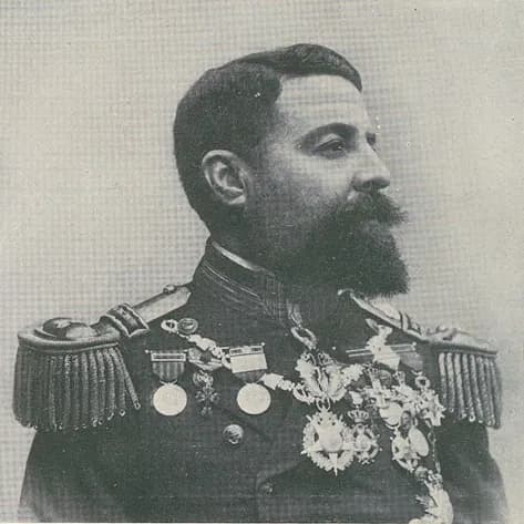 Portrait of a bearded naval officer in profile, with heavy epaulettes and rows of medals and decorations on his uniform.