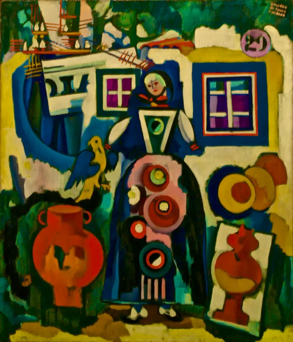 A flat, brightly coloured painting of a doll-like woman in a long dark blue dress decorated with red and pink discs, standing in front of a whitewashed house with two framed windows. A yellow and blue bird perches beside her, a large red clay pot stands to her left and another red vessel is framed to her right. Green foliage and a ship's rigging fill the top.