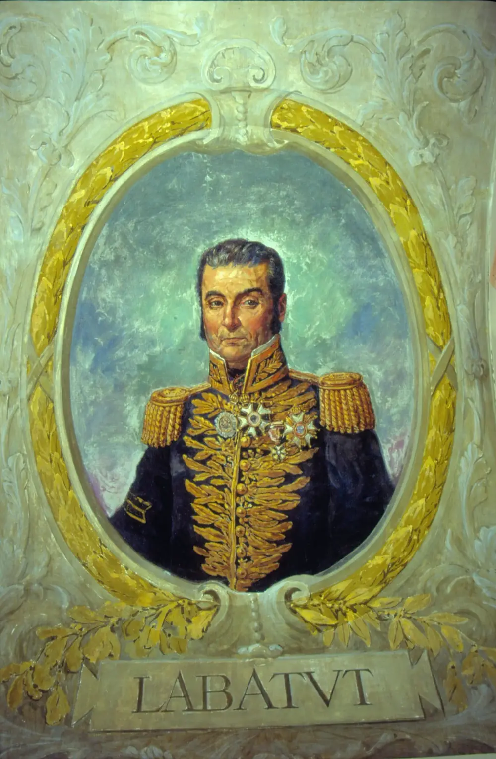 A painted oval portrait of a dark-haired man with long sideburns in a dark general's coat heavy with gold embroidery, epaulettes and decorations, framed by gilded laurel leaves above a plaque reading LABATUT.