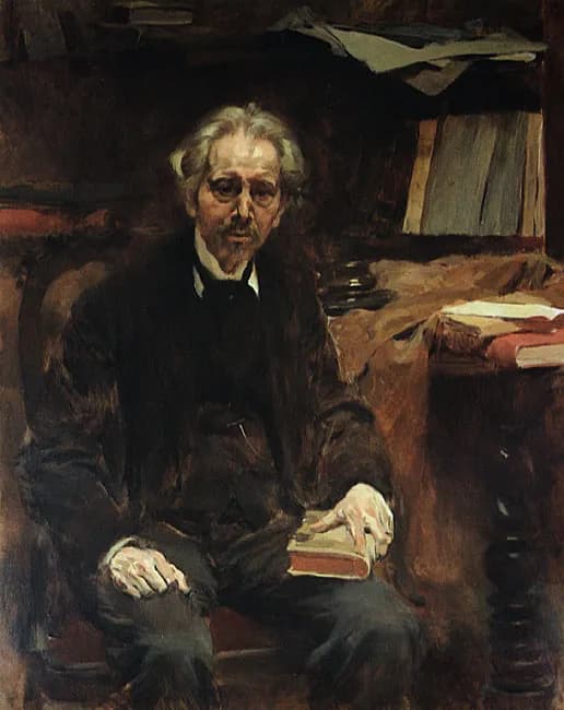 An elderly man with untidy grey hair and a small white beard sits in a dark armchair, wearing a dark coat. One hand rests on a closed red book on his knee. Behind him are shelves of books and papers, and more books lie on a table to the right.