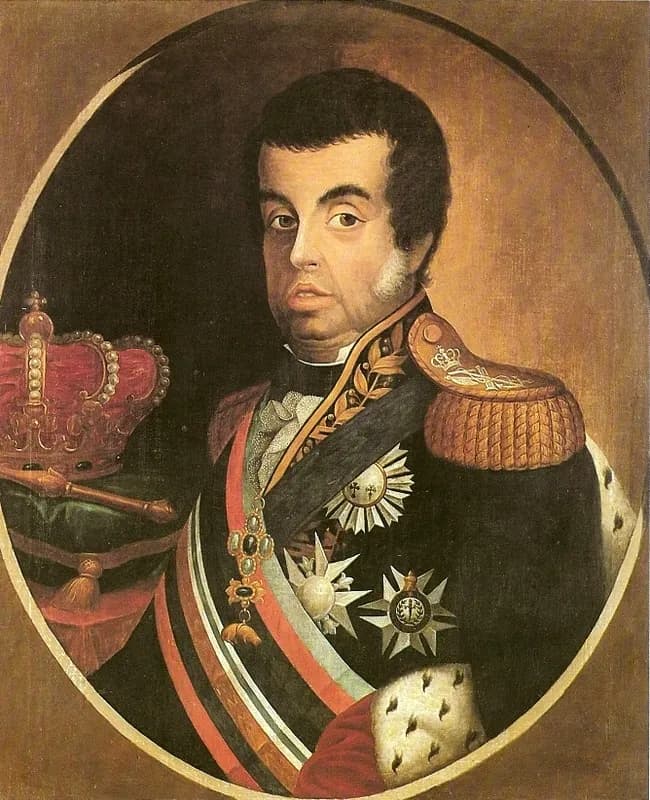 An oval oil portrait of a heavy-set man with dark hair and side-whiskers, in a dark uniform with gold epaulettes, a striped sash and several star-shaped orders. A red crown and a sceptre rest on a green cushion beside him.