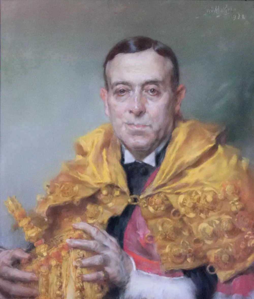 Painted portrait of an older man with dark slicked-back hair, wearing a shimmering yellow academic cape embroidered in gold over a red sash, his hands resting on a tasselled object.