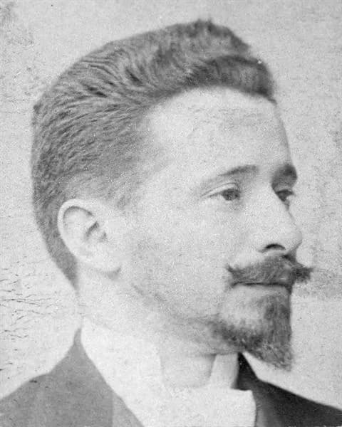 Head-and-shoulders photograph of a young man with short swept-back hair, a moustache and a pointed beard, turned slightly to the right.