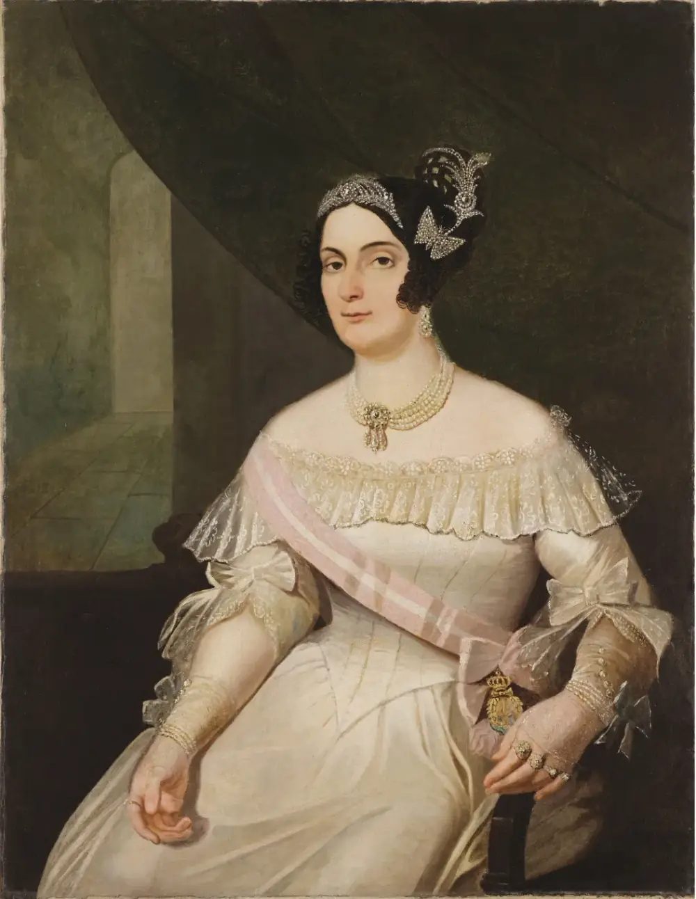 A seated woman with dark hair, a jewelled tiara and a feather ornament wears an off-the-shoulder white satin gown, a pink and white sash with an order badge, pearls and rings.