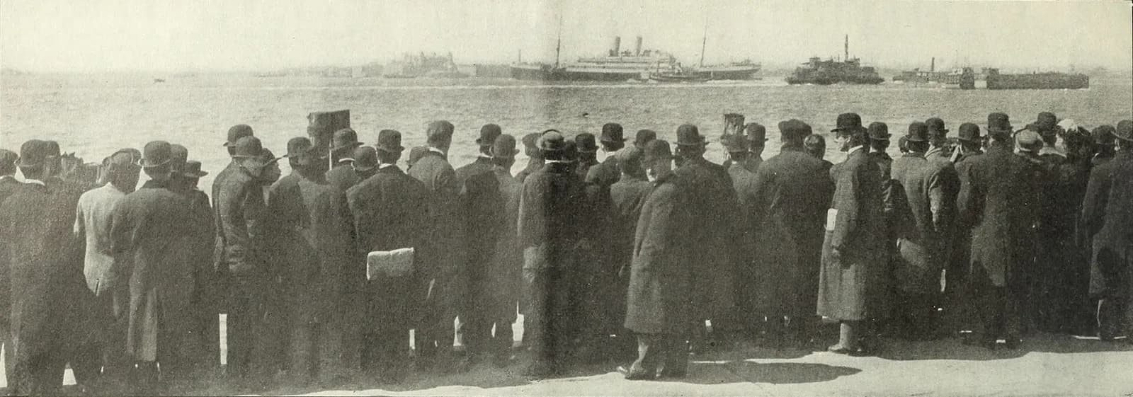 A long row of men in bowler hats and overcoats stand with their backs to the camera on a waterfront, watching a two-funnelled ocean liner pass across a wide harbour, with ferries and buildings on the far shore.