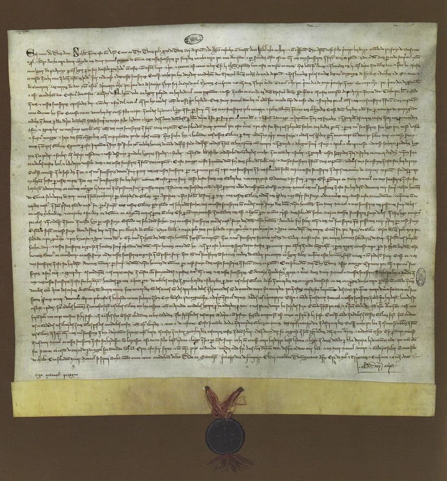 A large, almost square parchment sheet filled with close lines of medieval script. A folded strip along the bottom holds red and white cords from which hangs a round dark lead seal.