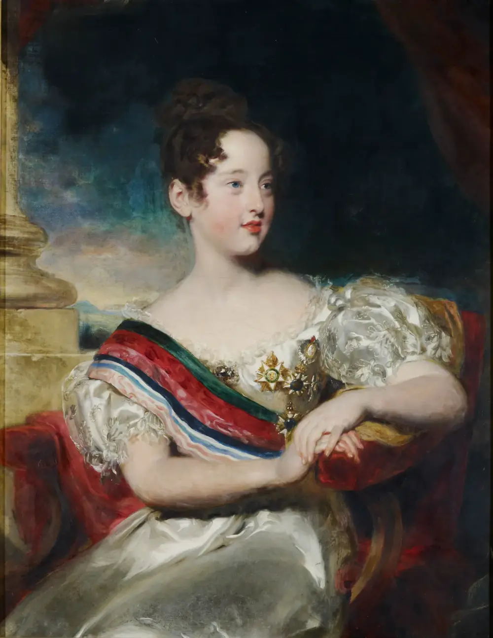 Oil portrait of a girl of about ten with dark curled hair, seated in a white satin dress, wearing a broad striped sash of red, green and blue and several jewelled orders, her arms resting on a red cushion beside a stone column.