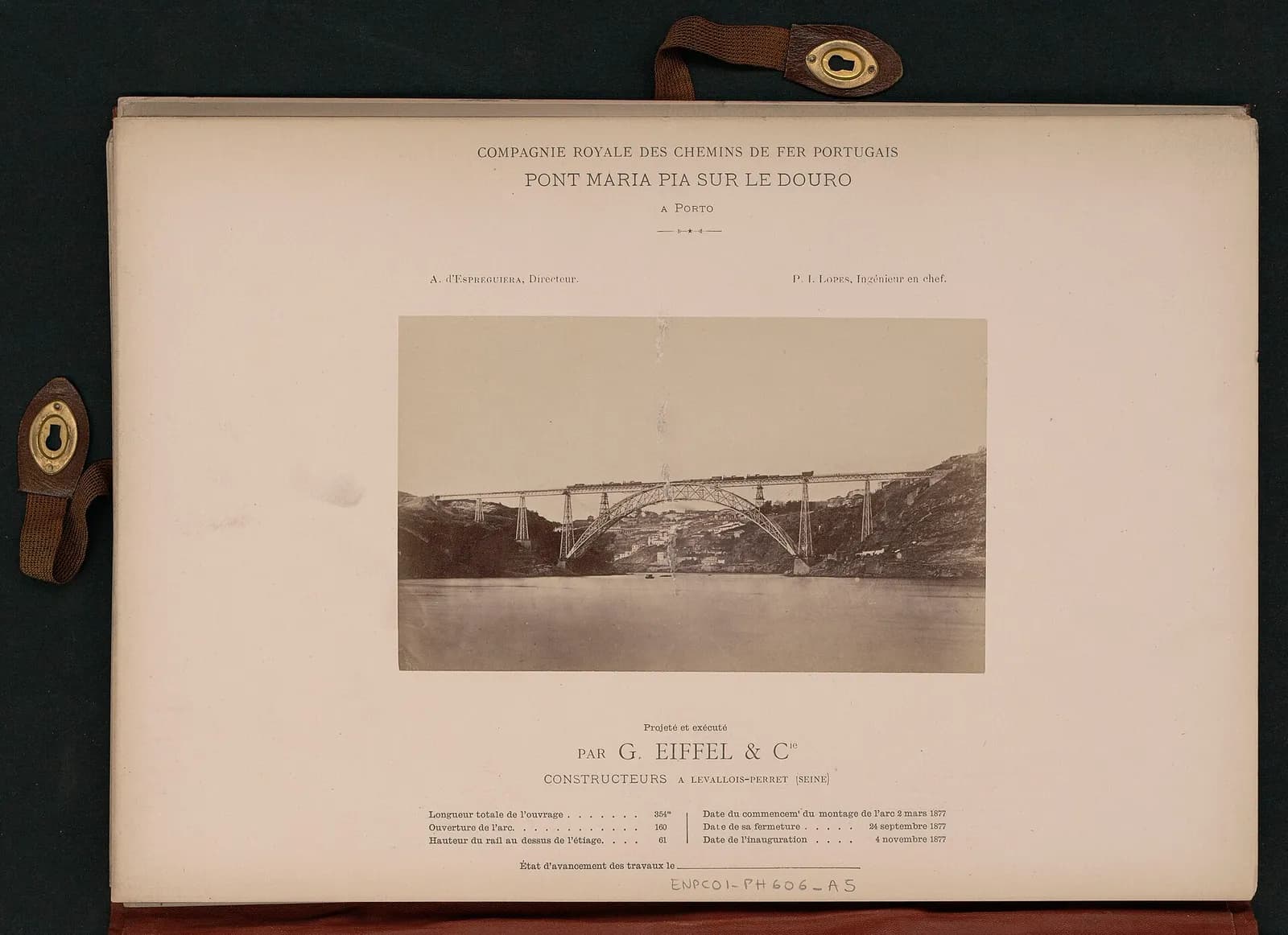 A page from an album with leather clasps. Printed headings name the Royal Portuguese Railway Company, the Maria Pia bridge over the Douro at Porto, and the company's director and chief engineer. In the middle is a sepia photograph of the finished iron arch bridge with a long train on its deck, and below are printed the builder's name, G. Eiffel and Co, and the bridge's dimensions and dates.