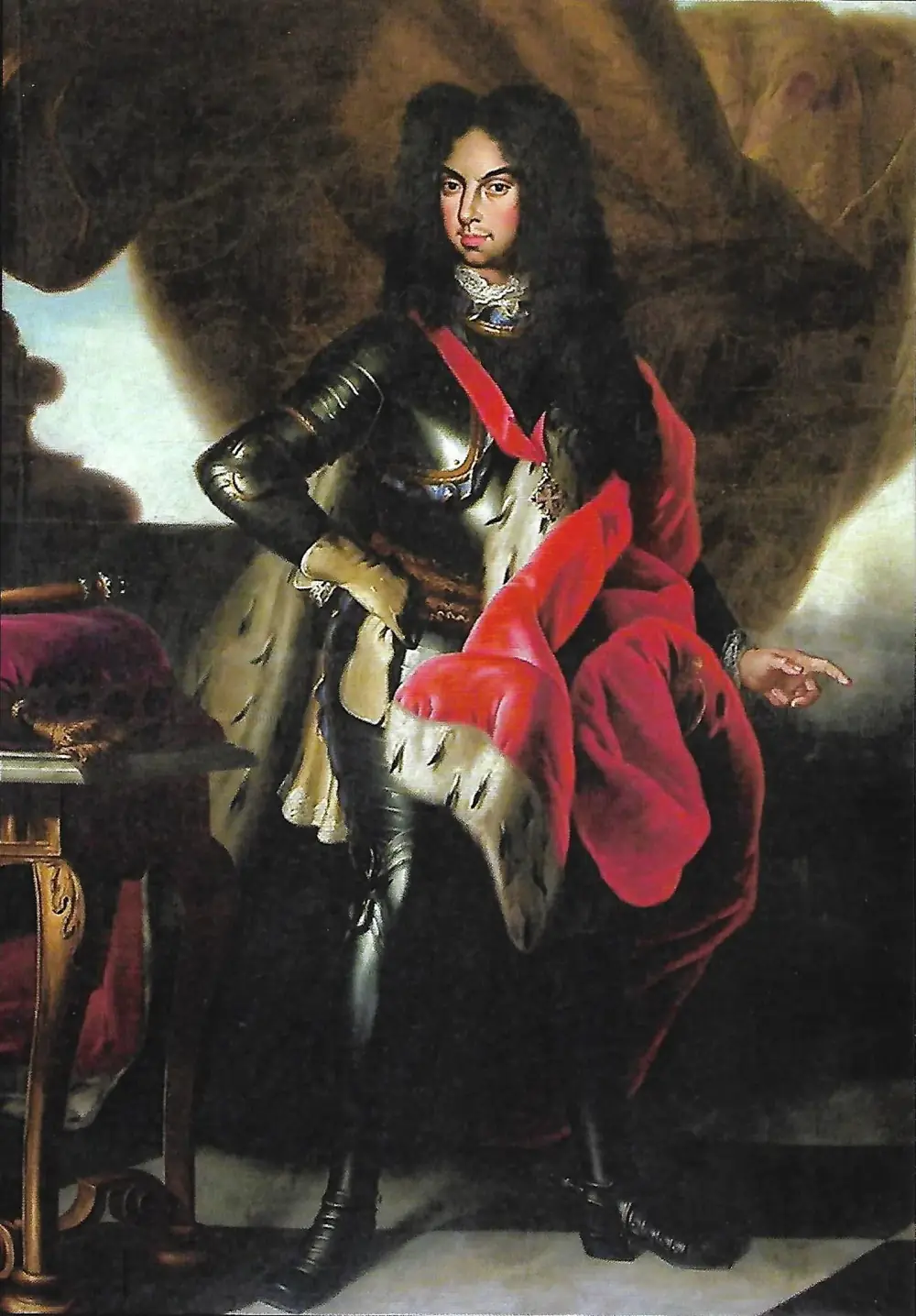 Full-length portrait of a man with long dark curls in polished armour, a red sash and a red, ermine-lined cloak, one hand on his hip and the other pointing down to his left.