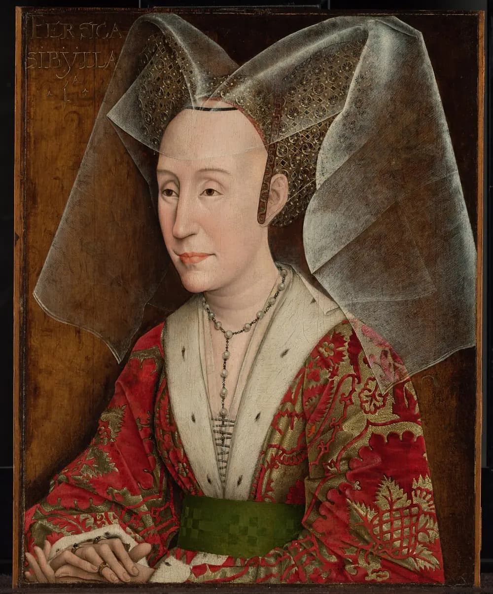 Half-length portrait of a pale middle-aged woman with a high plucked forehead, wearing a wide gauzy headdress over a jewelled cap, a red and gold brocade gown with white fur lapels, a green belt and a pearl necklace, her hands folded. Faded letters in the upper left corner read PERSICA SIBYLLA.