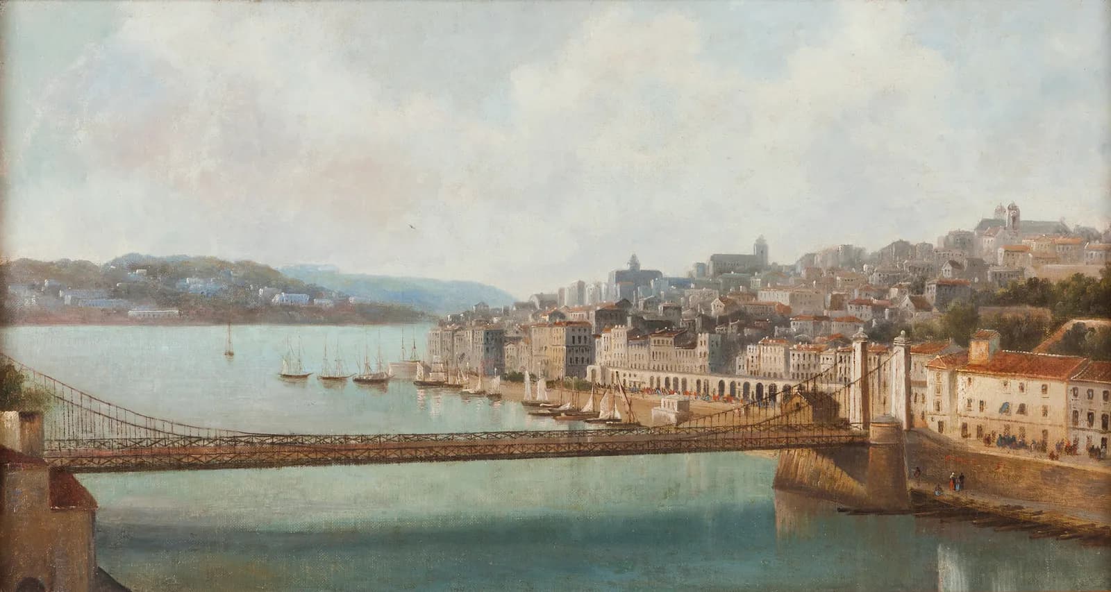An oil painting of a city on a river. Tall pale houses and an arcaded quay climb a hill on the right, under church towers. In the foreground a long, slender suspension bridge with a lattice railing crosses the water from a pair of stone obelisks on the right bank, and sailing ships lie at anchor downstream.