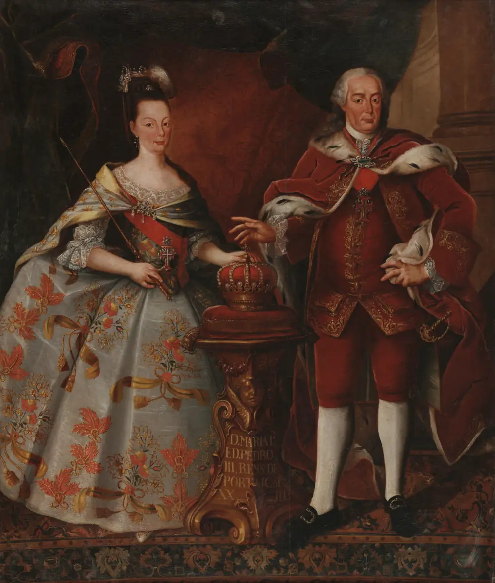 Full-length double portrait of a woman in a pale silk gown embroidered with red flowers, holding a sceptre, and a stout grey-haired man in a red velvet suit and ermine-lined cloak; between them a crown rests on a cushion on a carved pedestal inscribed with their names.