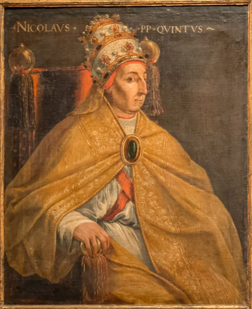 A painted portrait of an elderly clean-shaven man in a jewelled papal tiara and a heavy gold cope fastened with a large green stone, seated on a red chair. The inscription reads Nicolaus PP Quintus.
