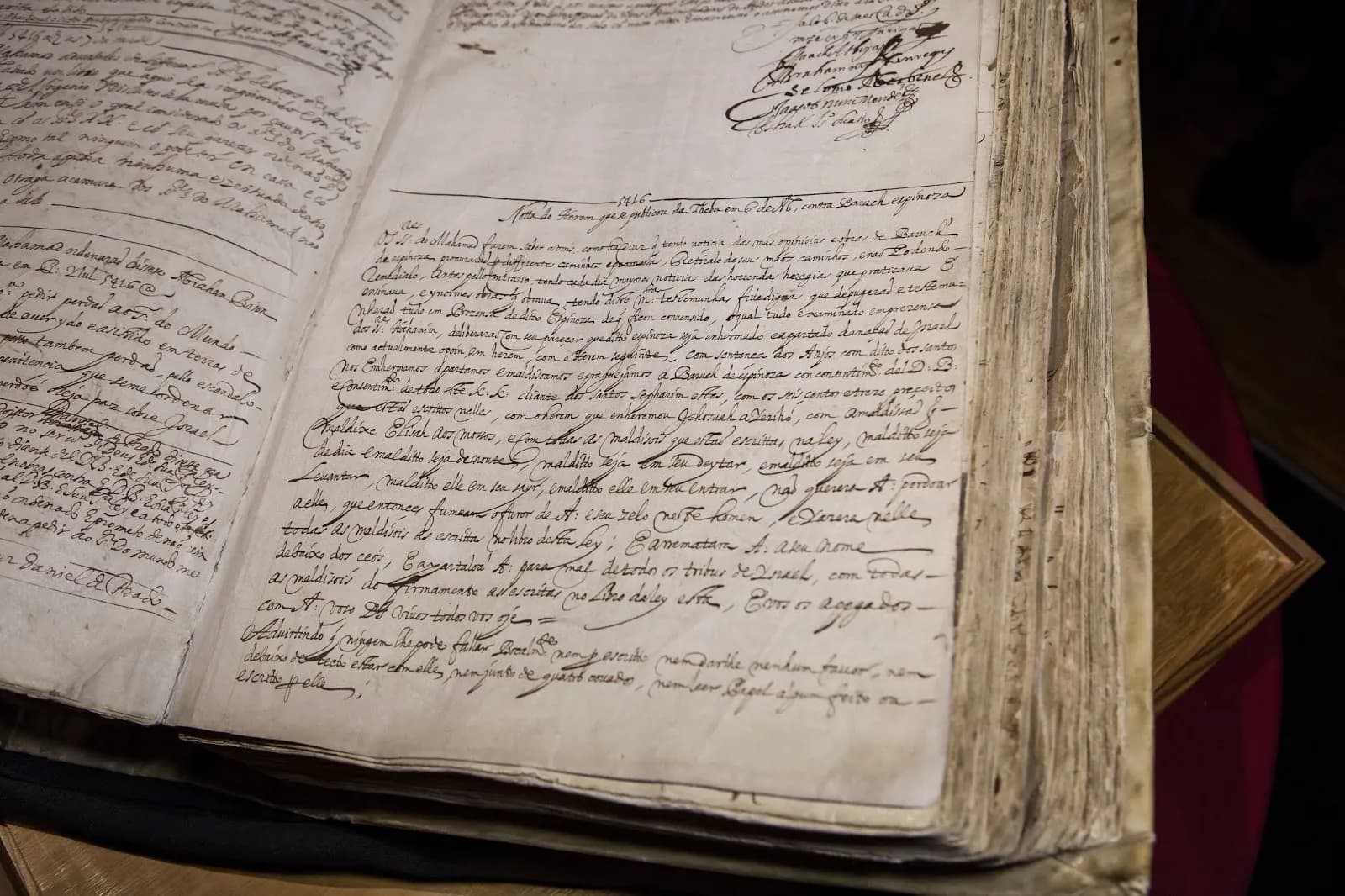 An old bound register lies open. The right-hand page is covered in dense seventeenth-century handwriting in brown ink beneath a short heading and a line ruled across the page, with signatures at the top right.