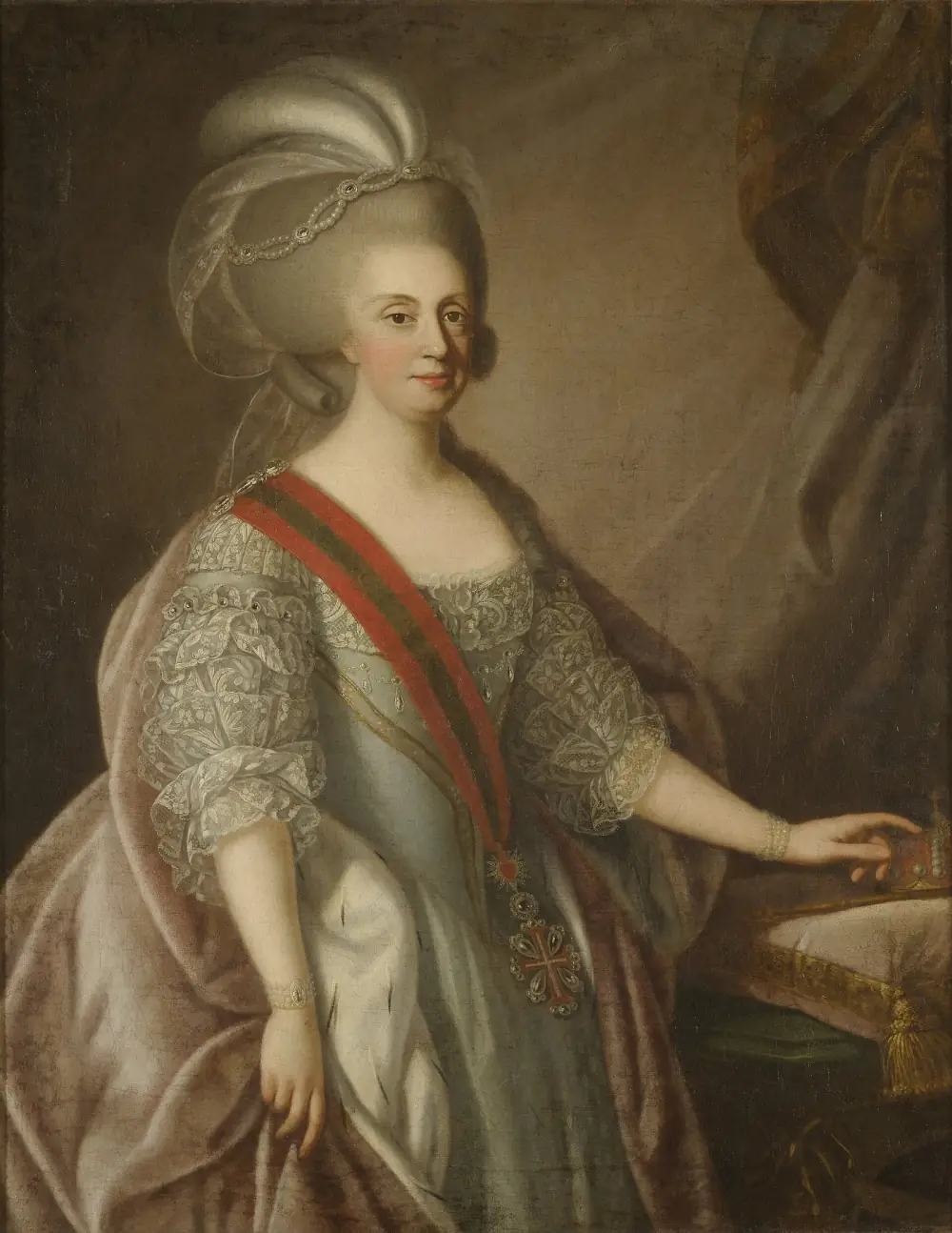 Three-quarter-length oil portrait of a woman in a pale blue silk dress with lace sleeves and an ermine-lined mantle, her powdered hair dressed high with pearls and white plumes. A red and green sash crosses her chest and her left hand rests on a crown set on a cushion.