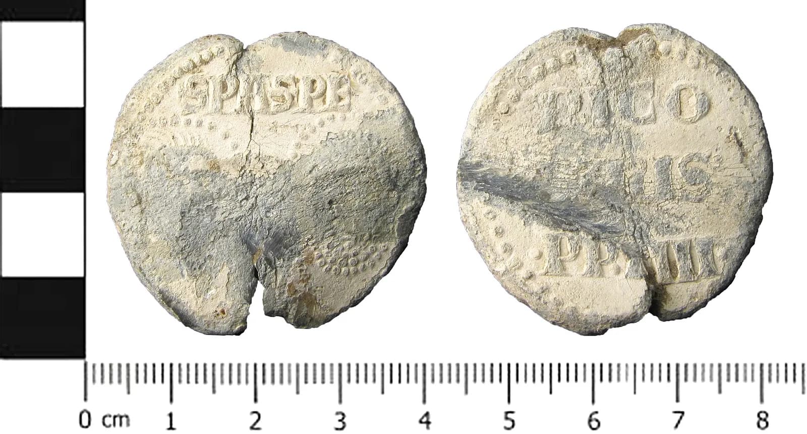 Both faces of a worn, cream-coloured lead disc beside a centimetre scale, about 3.6 cm across. One face has the letters SPASPE above worn dotted borders; the other reads NICO, LAUS and PP IIII in three lines.